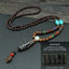 Dark beaded necklace with turquoise-colored accents and a black patterned tube pendant