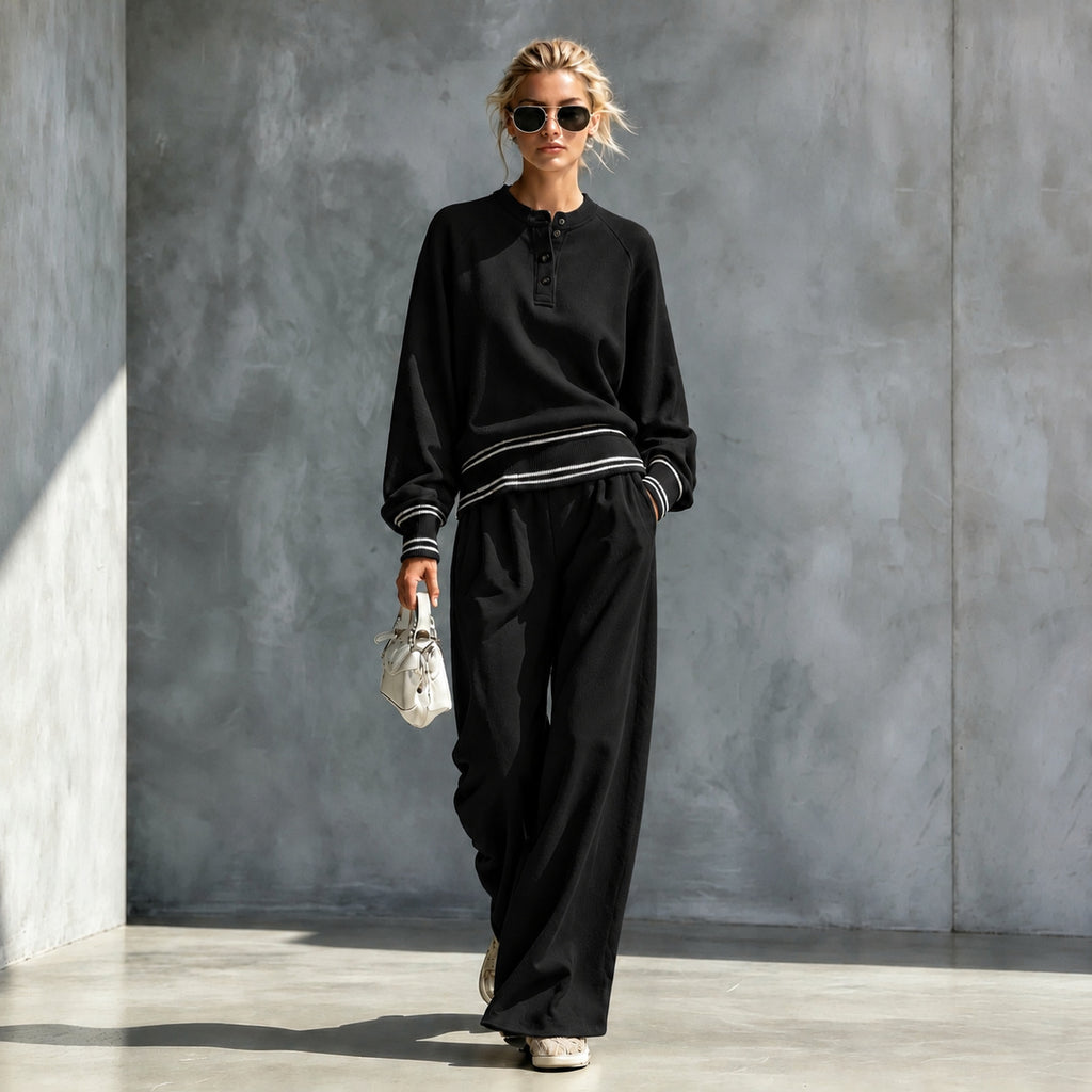 Black button-neck top and wide-leg pants set with striped trim, worn by a model