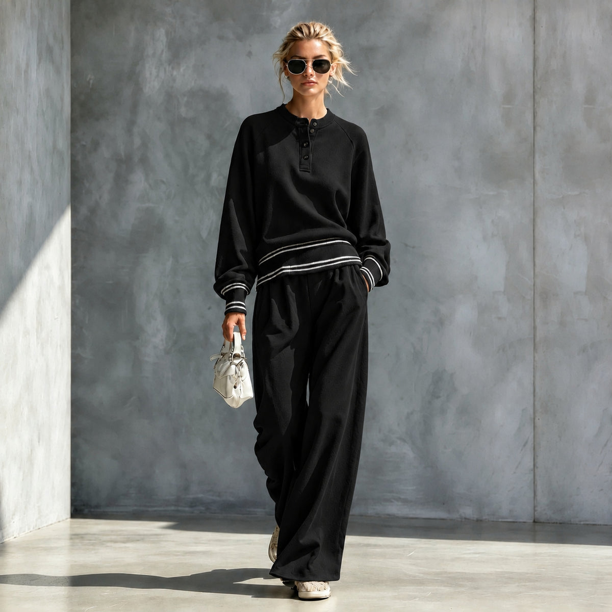 Black button-neck top and wide-leg pants set with striped trim, worn by a model