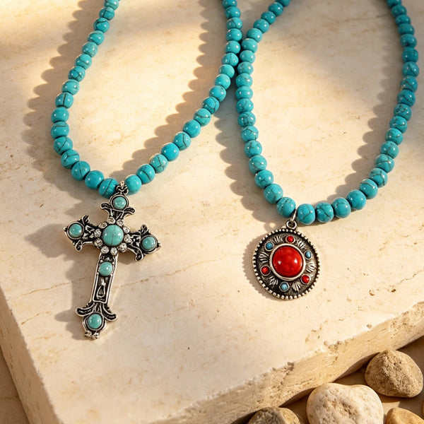 Turquoise-colored beaded necklaces with cross and round pendants on a pale stone surface