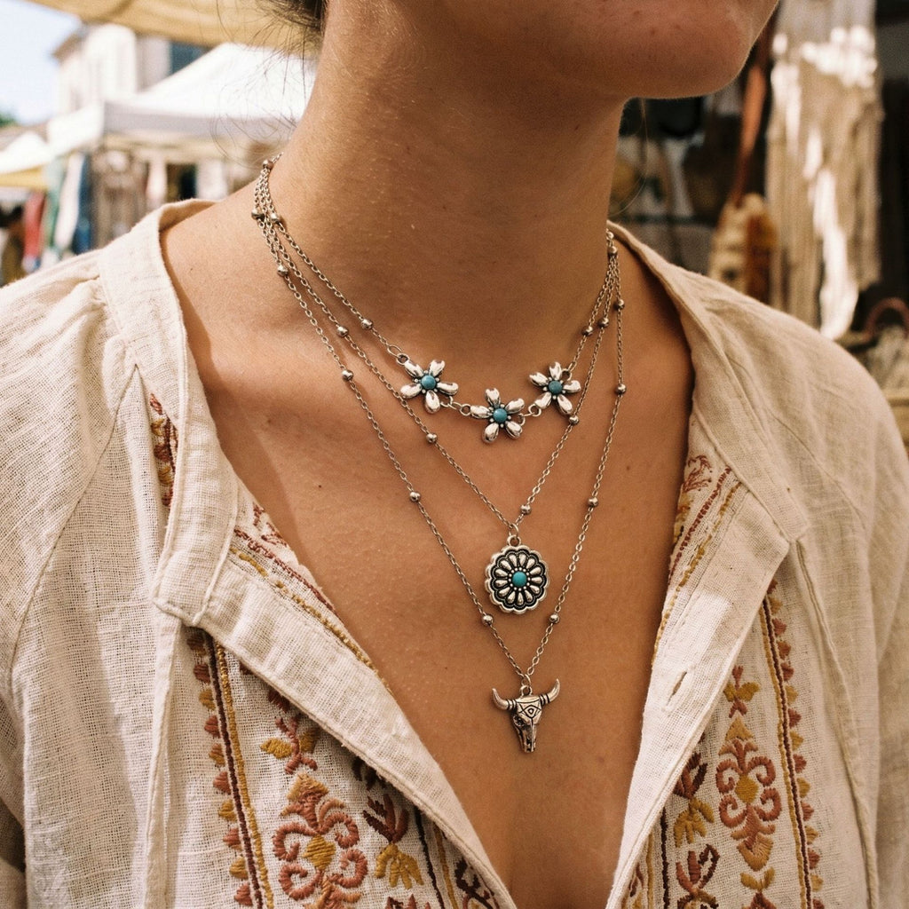 Layered silver-tone necklace with floral accents, round pendant and hanging charms