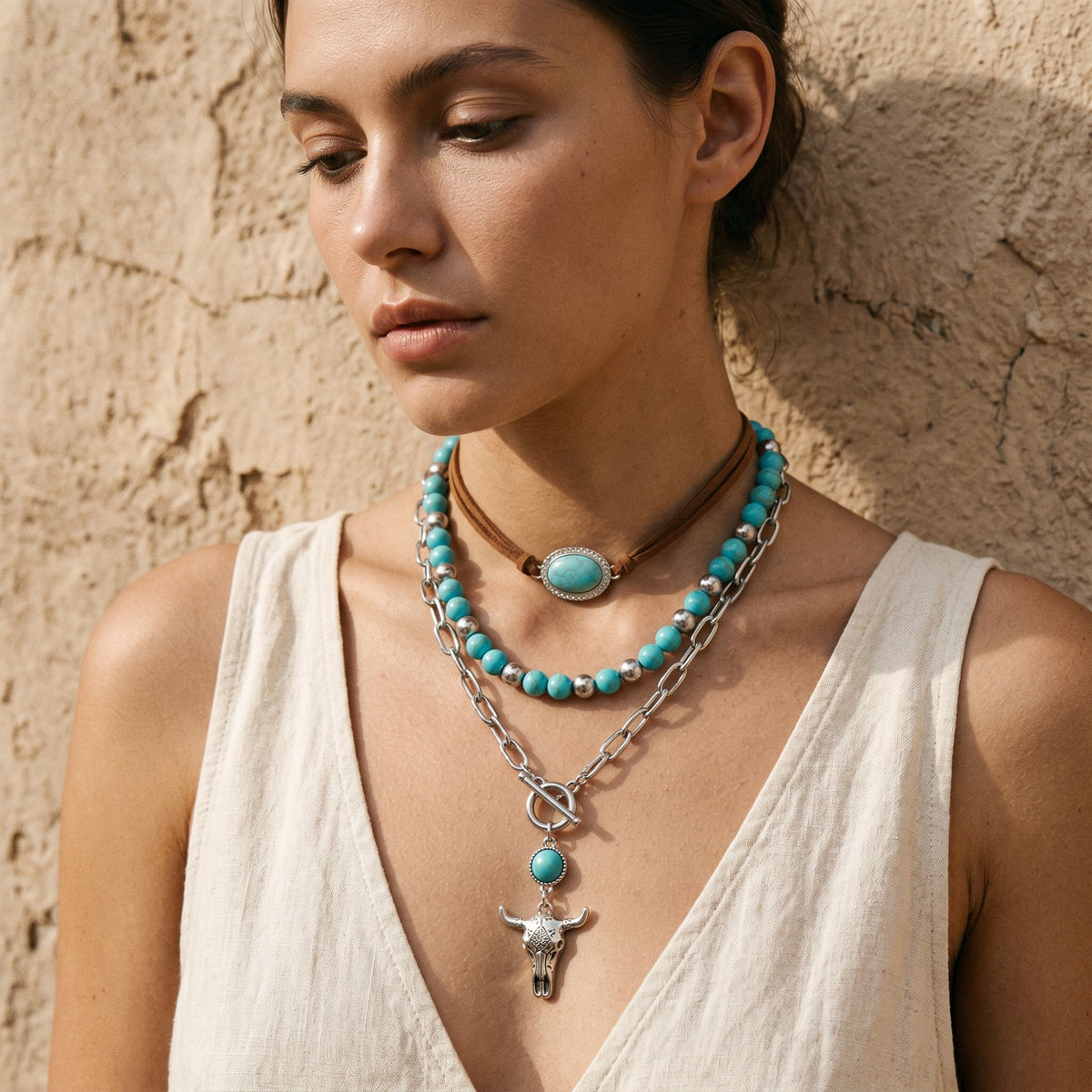 Model wearing turquoise-colored layered necklaces with a cross pendant