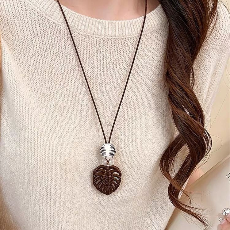 Textured heart pendant necklace on a dark cord, worn with a pale knit top