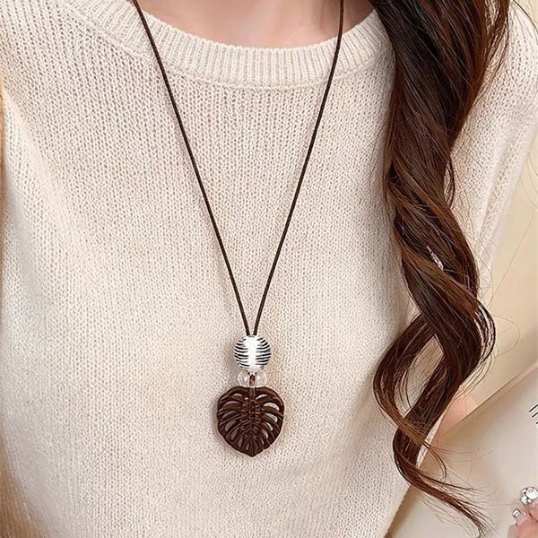 Textured heart pendant necklace on a dark cord, worn with a pale knit top