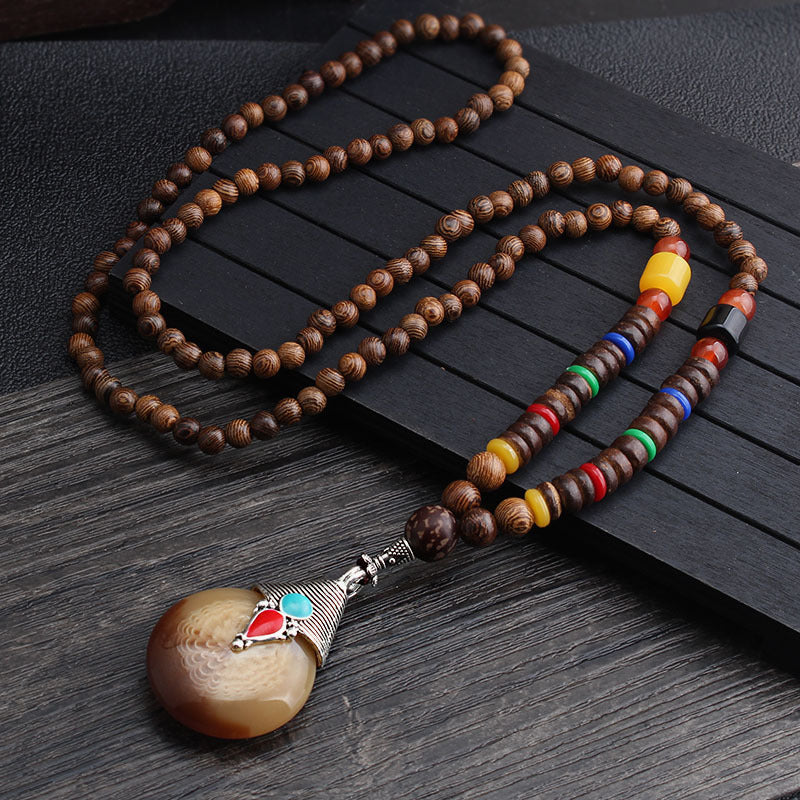 Brown beaded necklace with multicolor disc beads and round two-tone pendant