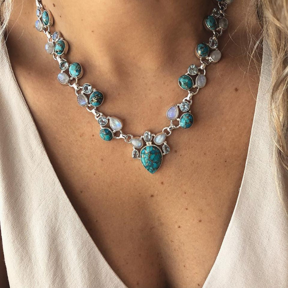 Silver-tone floral necklace with turquoise-colored oval accents, close-up on a model