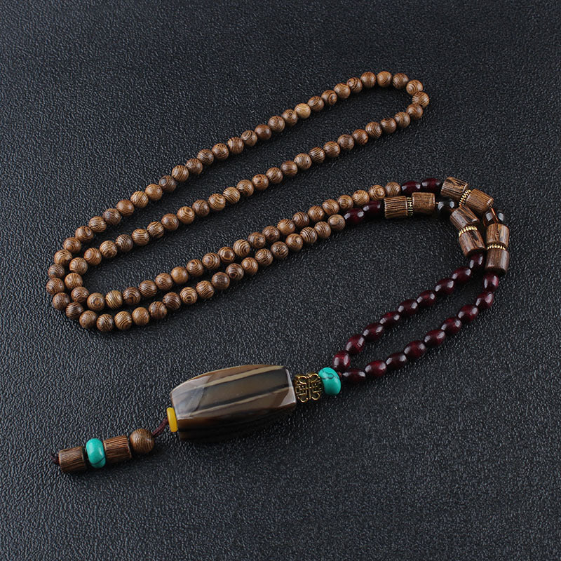 Long brown beaded necklace with dark rectangular pendant and turquoise-colored accents