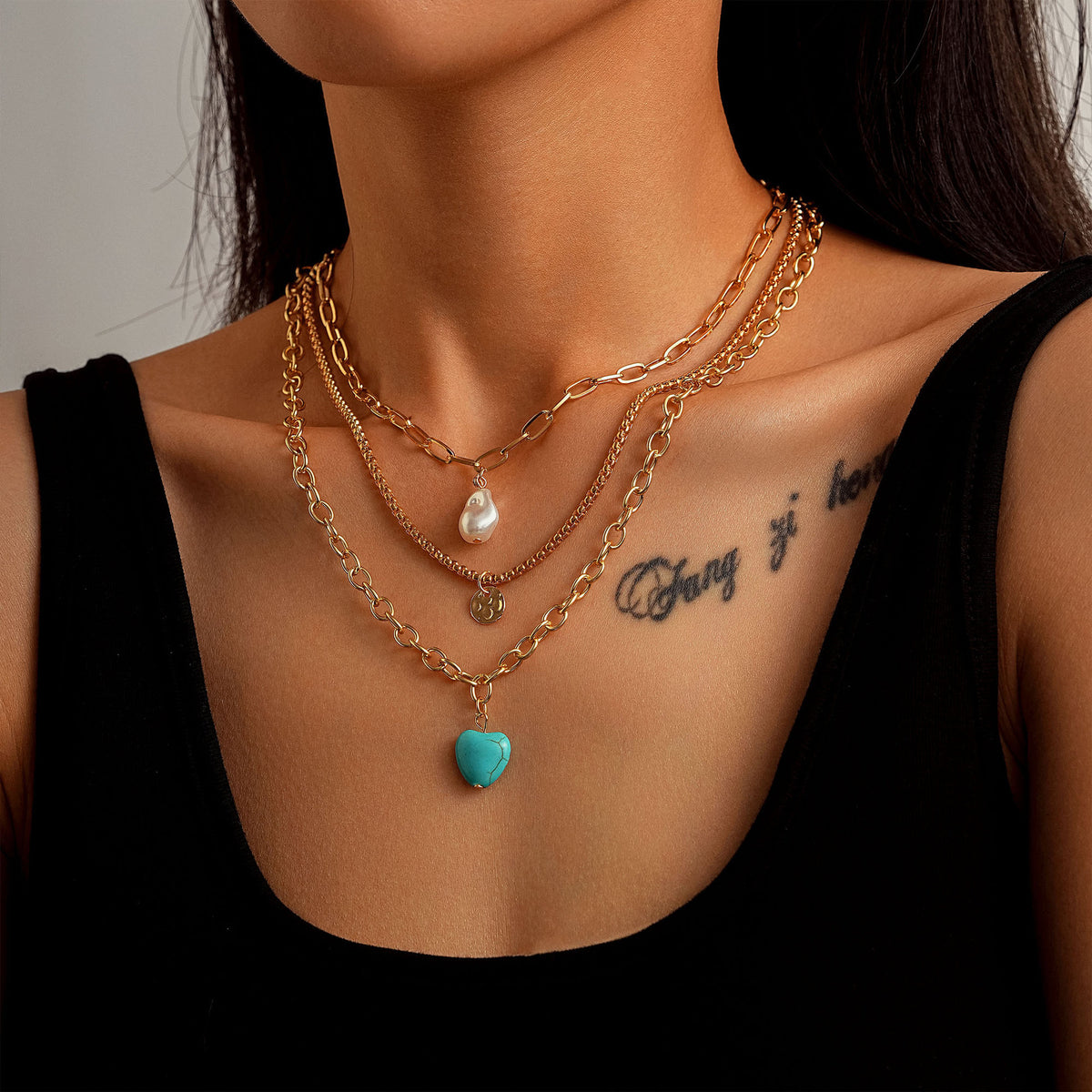 Layered gold-tone necklaces with clear and turquoise-colored drop accents