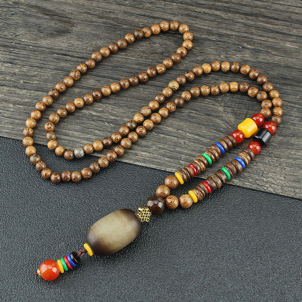 Brown beaded necklace with multicolor discs and pale oval pendant on dark wood