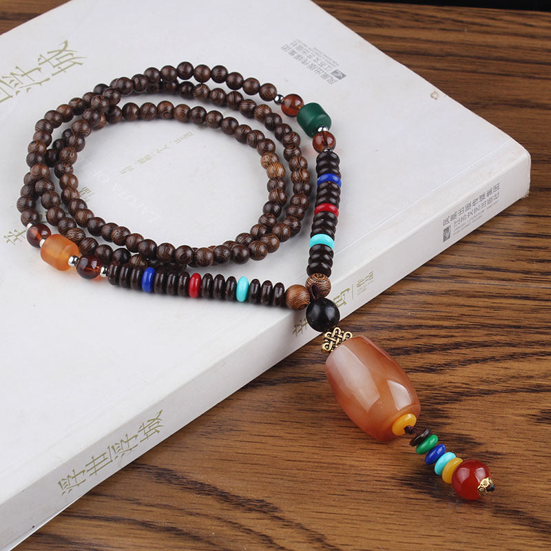 Brown beaded necklace with amber-colored oval pendant and multicolor accents on a white book