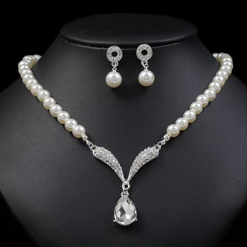 White pearl-style necklace with teardrop pendant and matching drop earrings on a black bust