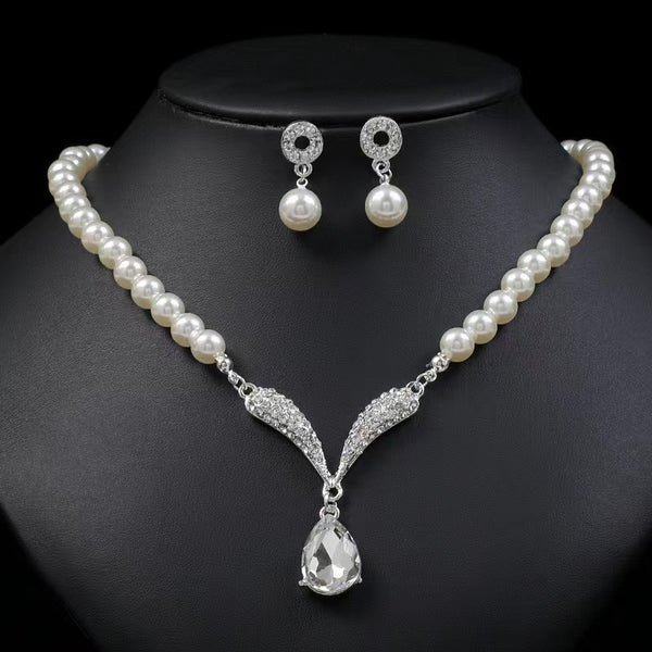 White pearl-style necklace with teardrop pendant and matching drop earrings on a black bust