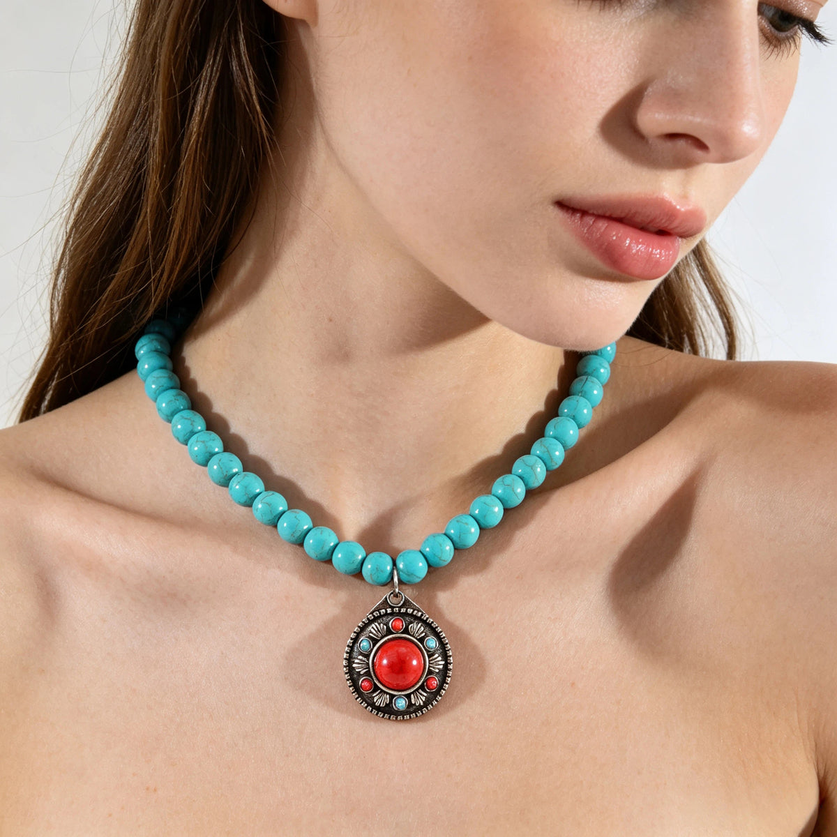 Model wearing a turquoise-colored beaded necklace with red round pendant