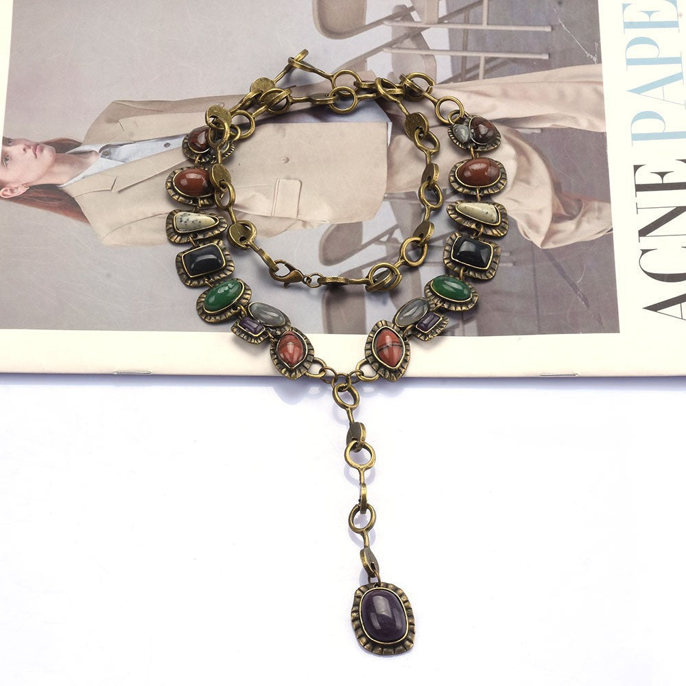 Multicolor oval-accent necklace with long purple drop pendant displayed on a magazine