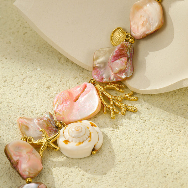Close-up of pink shell-style necklace beads with gold-tone coral and spiral shell charms