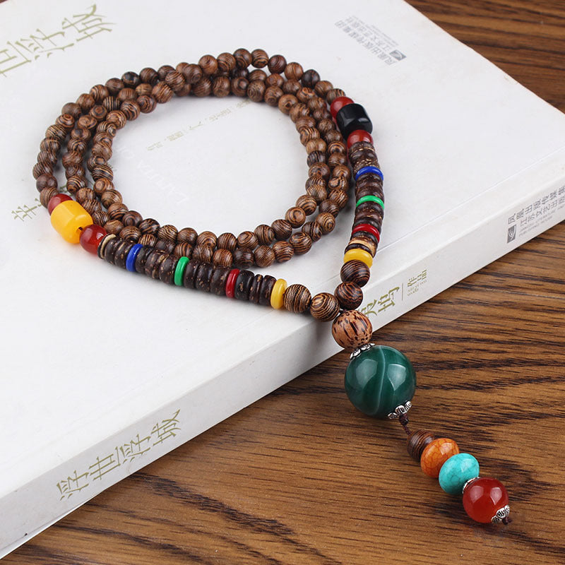 Brown beaded necklace with dark green drop pendant and multicolor accents on a white book