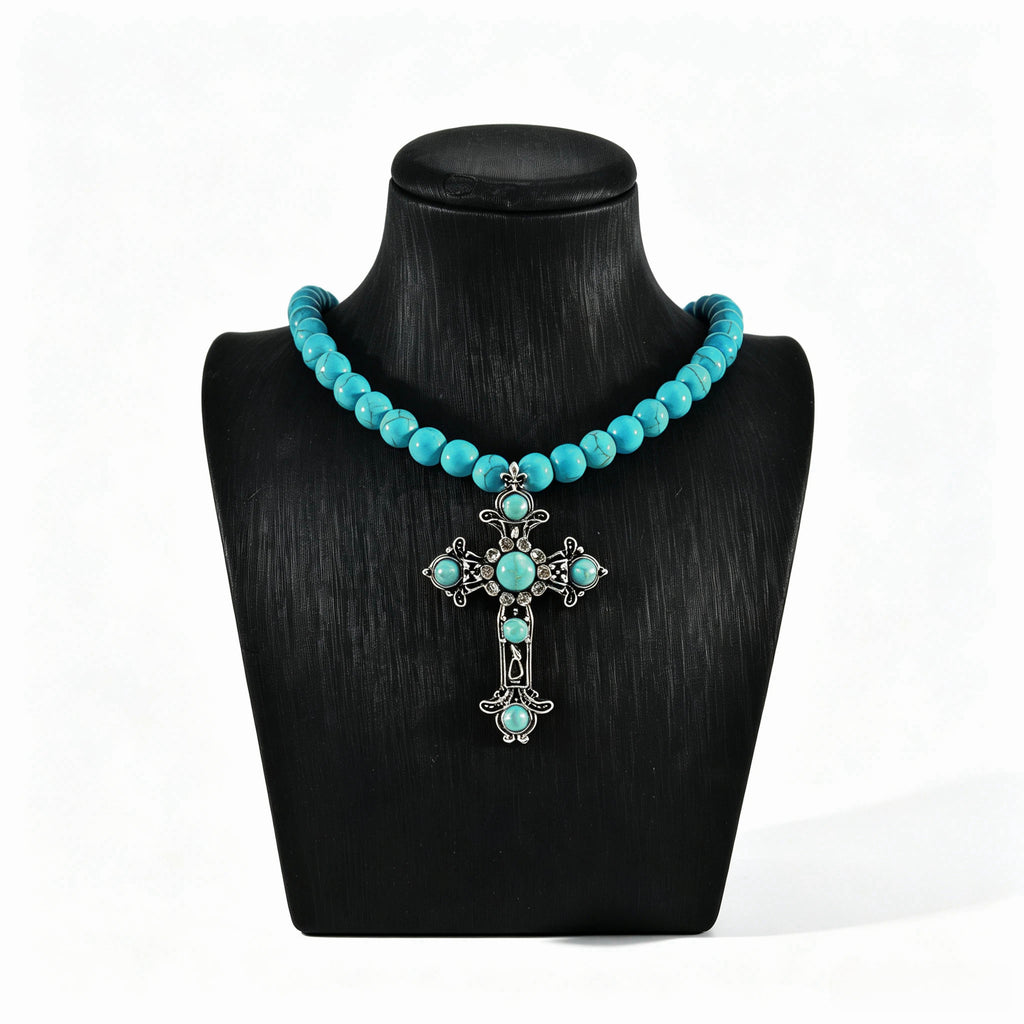 Turquoise-colored beaded necklace with ornate cross pendant on a black display bust