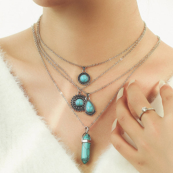 Layered silver-tone necklaces with turquoise-colored round and elongated pendants
