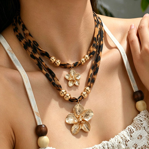 Model wearing a layered leopard-print necklace with two gold-tone flower pendants