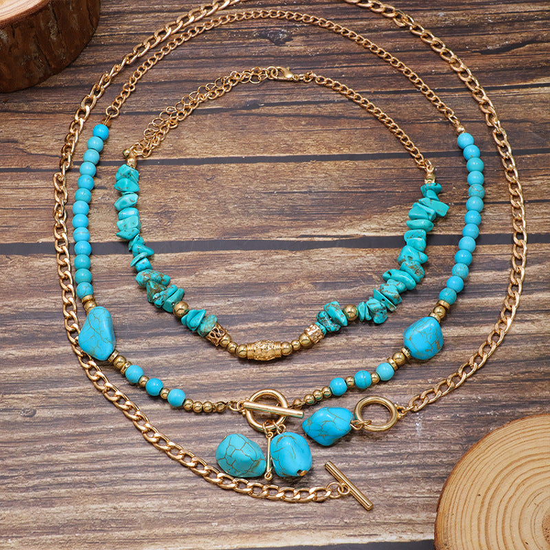 Layered turquoise-colored and gold-tone necklace arranged on a wooden surface