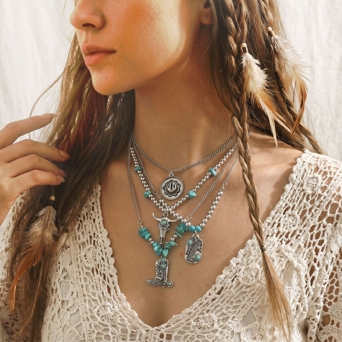 Layered silver-tone necklaces with turquoise-colored accents and a large cross pendant