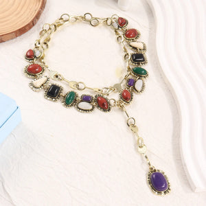 Multicolor oval-accent necklace with gold-tone chain and purple drop pendant on fabric
