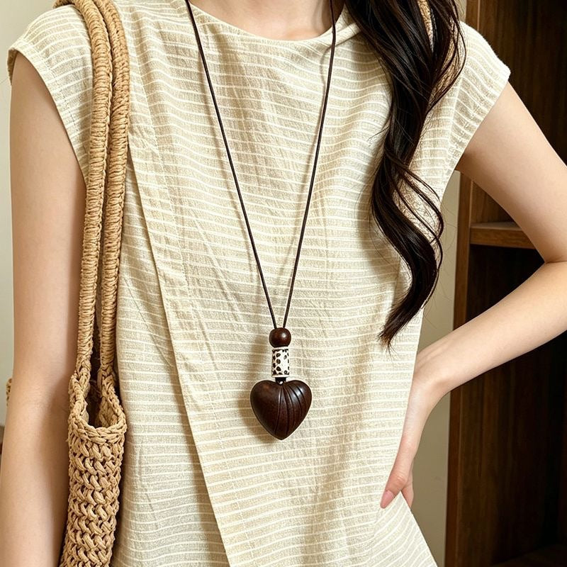 Brown heart pendant necklace with round accent bead, close-up on a model