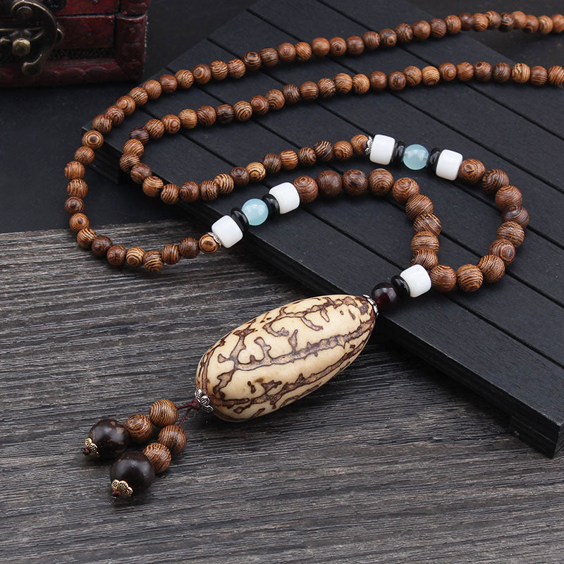 Brown beaded necklace with patterned oval pendant and pale blue and white accent beads