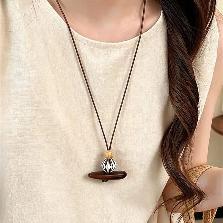 Brown bar pendant necklace on a long cord, worn with a cream top