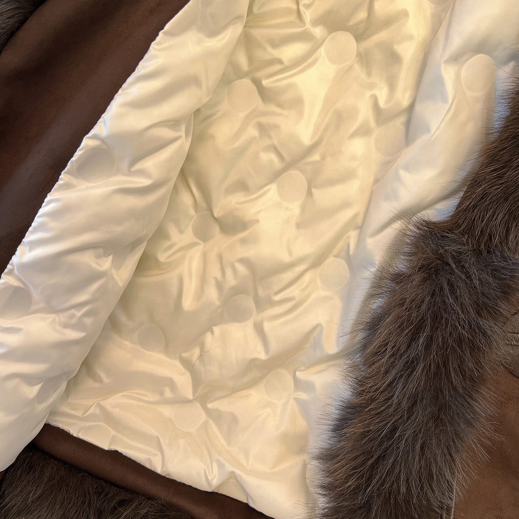 Cream quilted interior lining of a brown coat with dark plush trim