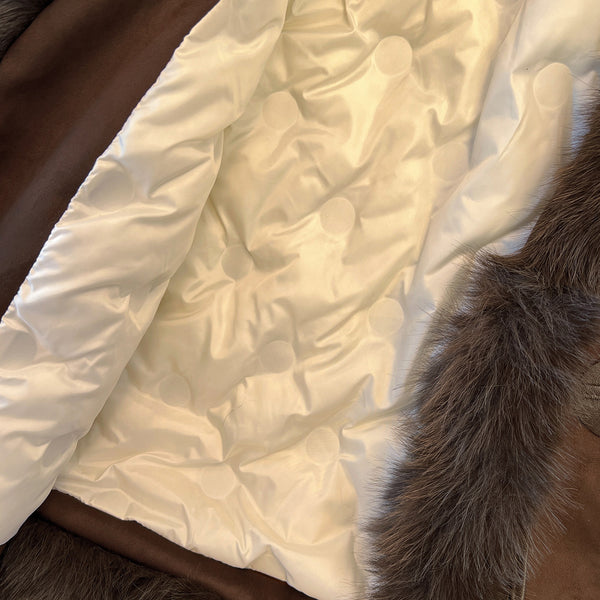 Cream quilted interior lining of a brown coat with dark plush trim