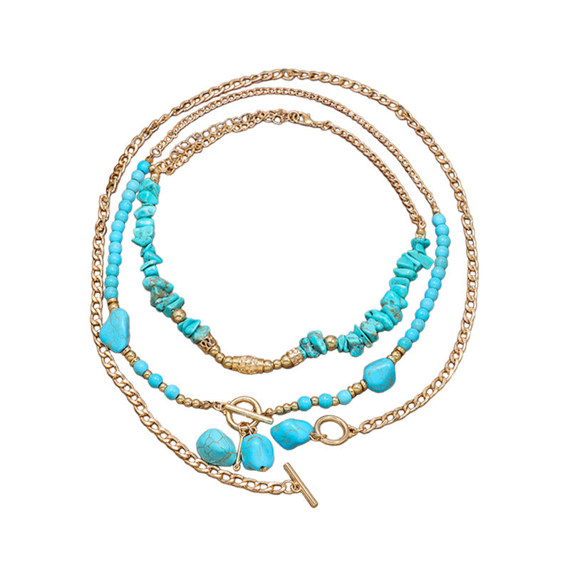 Layered turquoise-colored beaded necklace with gold-tone links on white