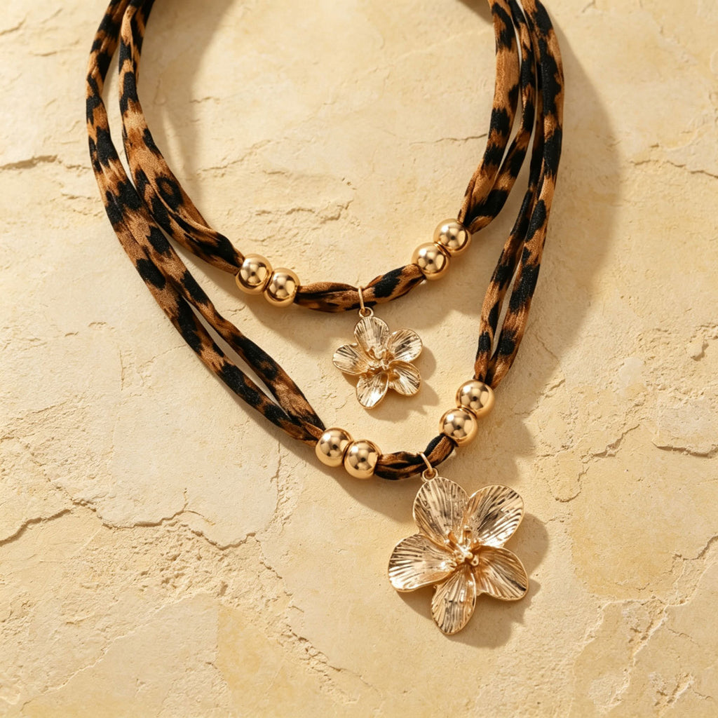 Double-layer leopard-print necklace with gold-tone flower pendants on pale stone