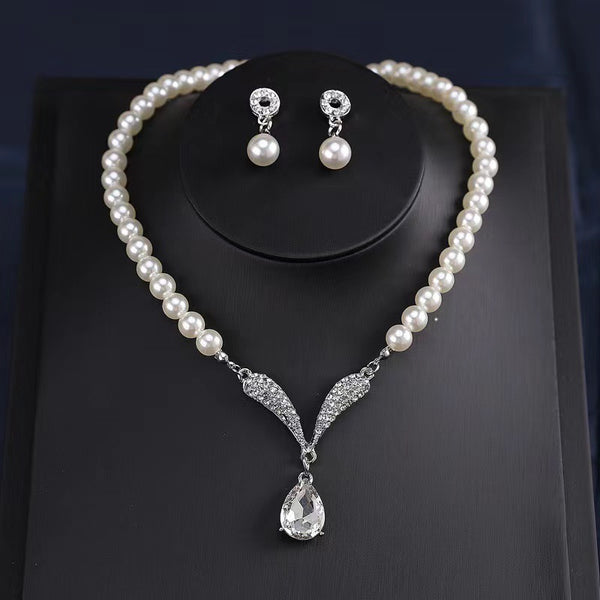 White pearl-style necklace with teardrop pendant and matching earrings in a presentation box