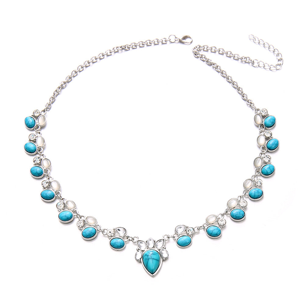 Silver-tone necklace with alternating clear and turquoise-colored teardrop accents