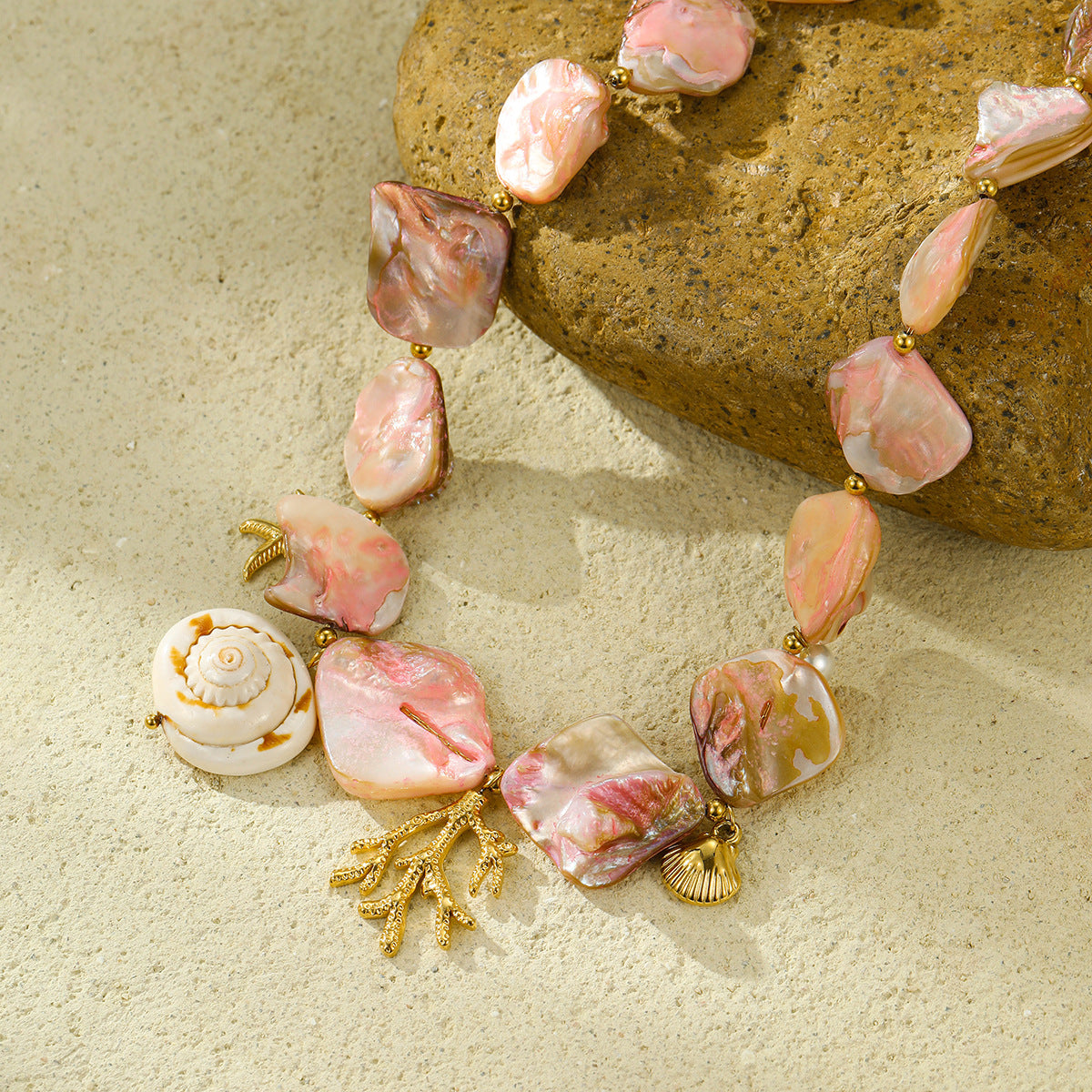 Close-up of pink shell-style beads and gold-tone coral and shell charms