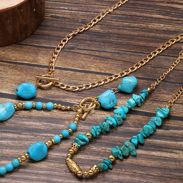 Close-up of turquoise-colored necklace beads, gold-tone links and decorative pendants
