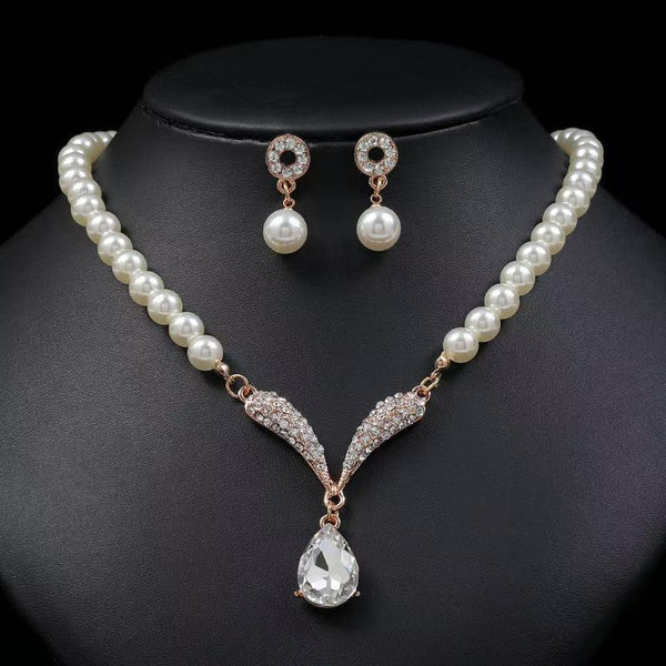 Pearl-style necklace with clear teardrop pendant and matching earrings on a black bust