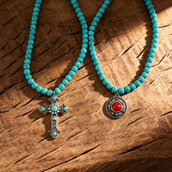 Turquoise-colored beaded necklaces with cross and red round pendants on wood