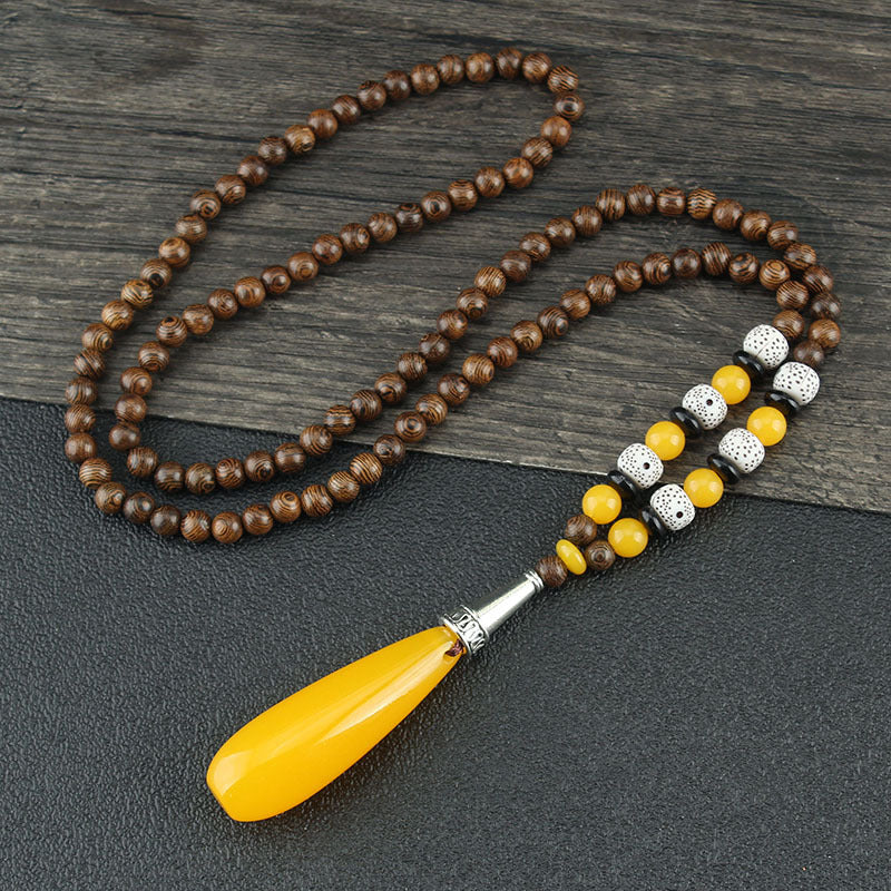 Brown beaded necklace with yellow drop pendant and black and white flower-patterned beads