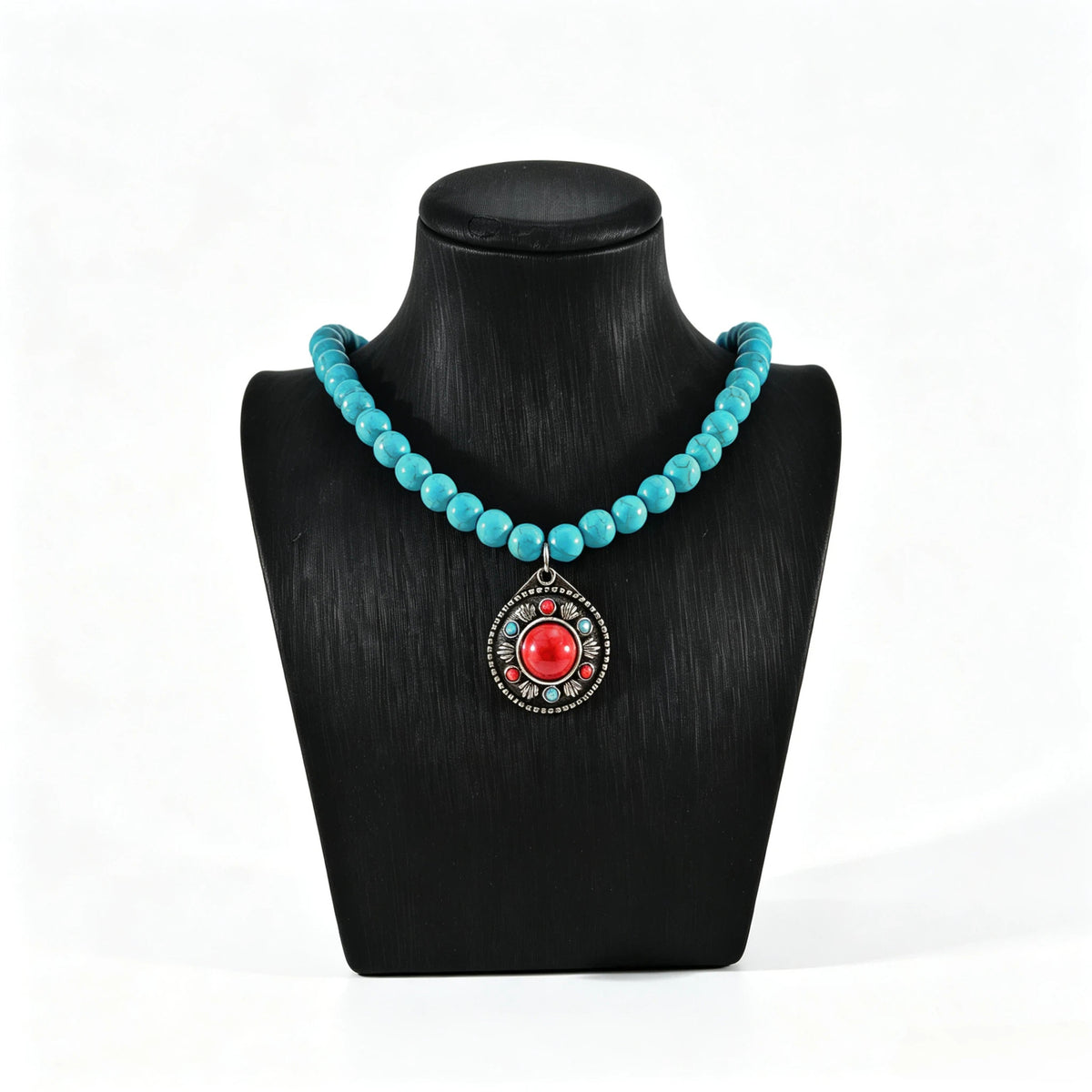 Turquoise-colored beaded necklace with red round pendant on a black display bust