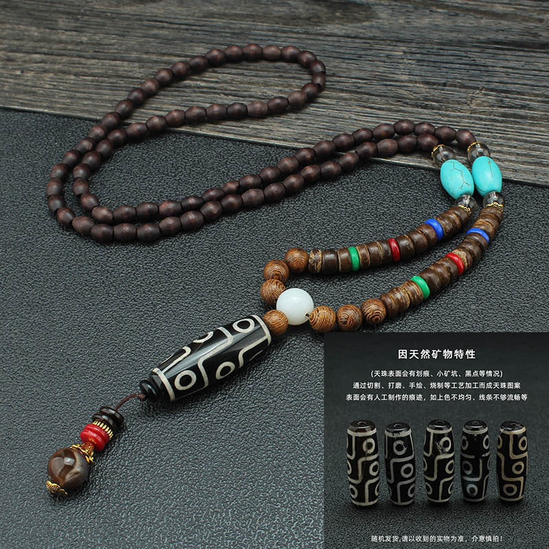 Dark beaded necklace with turquoise-colored accents and a black patterned tube pendant