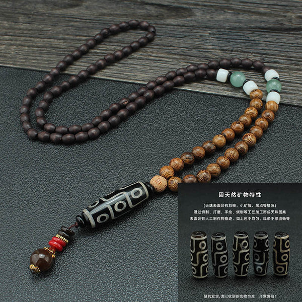 Dark beaded necklace with pale accent beads and a black patterned tube pendant