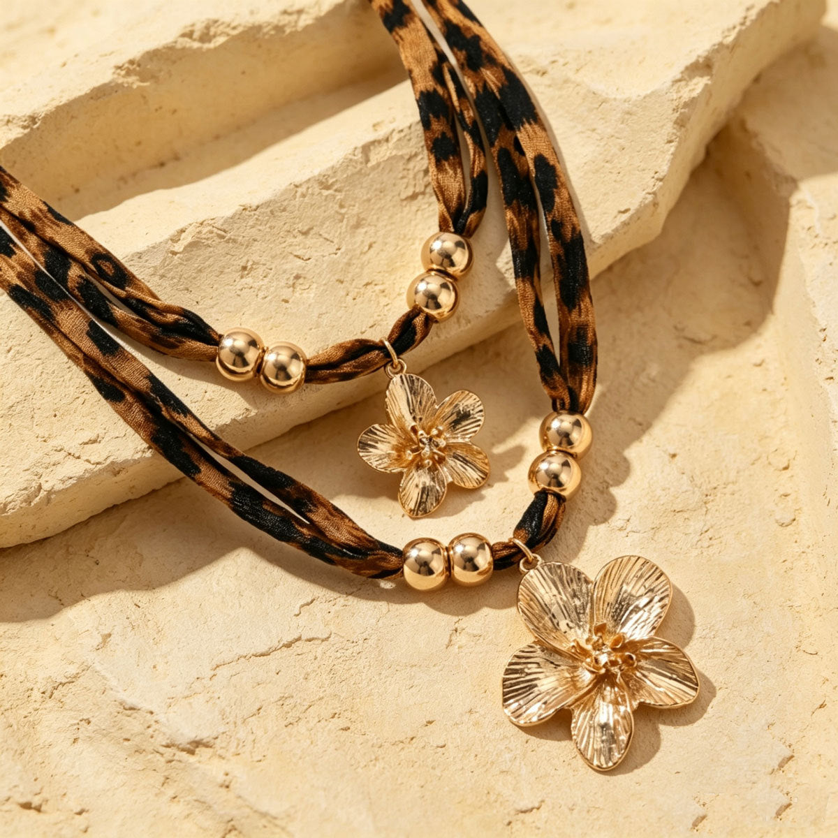 Close-up of leopard-print necklace cords, gold-tone beads and flower pendants