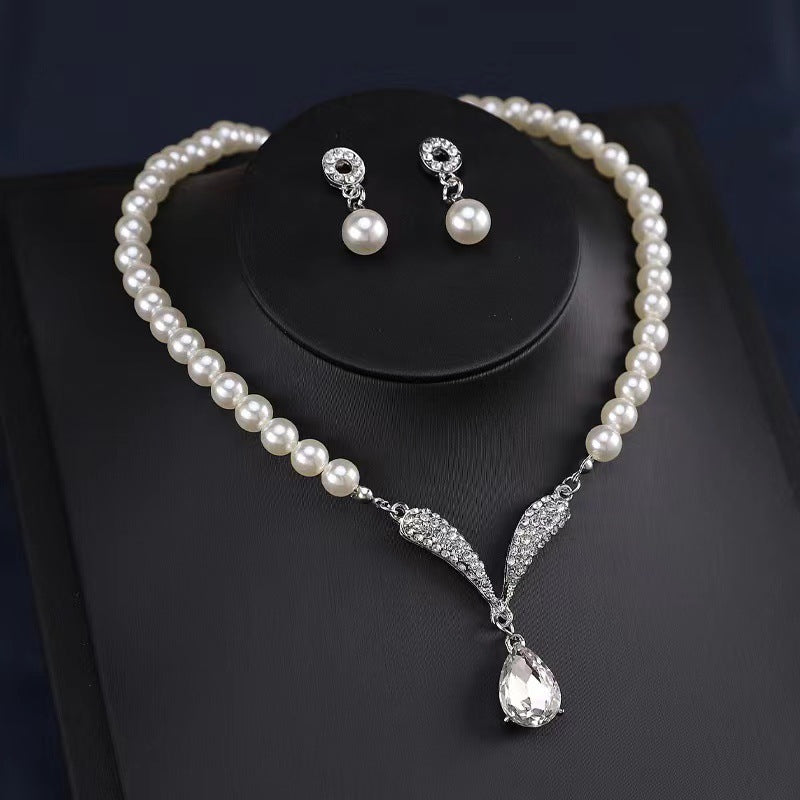White pearl-style necklace and matching teardrop earrings arranged in a black display box