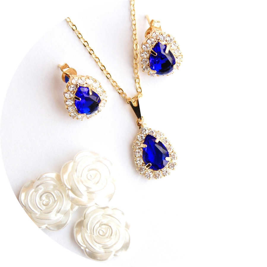 Jewelry set with blue gemstones and gold accents on a white background
